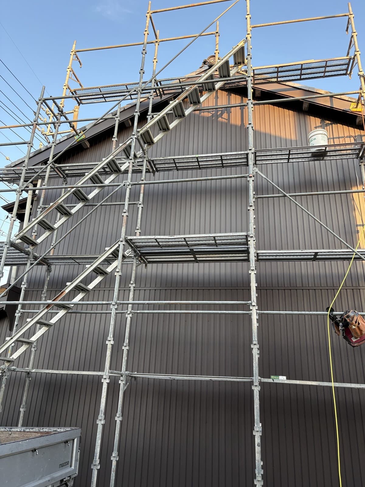 施工後の建物。こげ茶色の成型角波の外壁と板金を巻いた破風